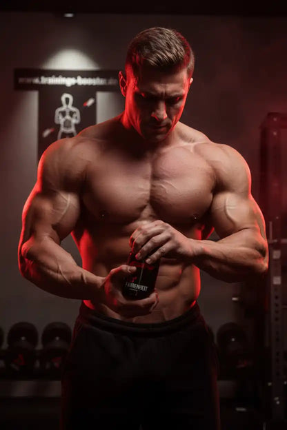 Muskulöser Mann mit Fatburner-Flasche im Fitnessstudio, ideal für Sportnahrung und Training