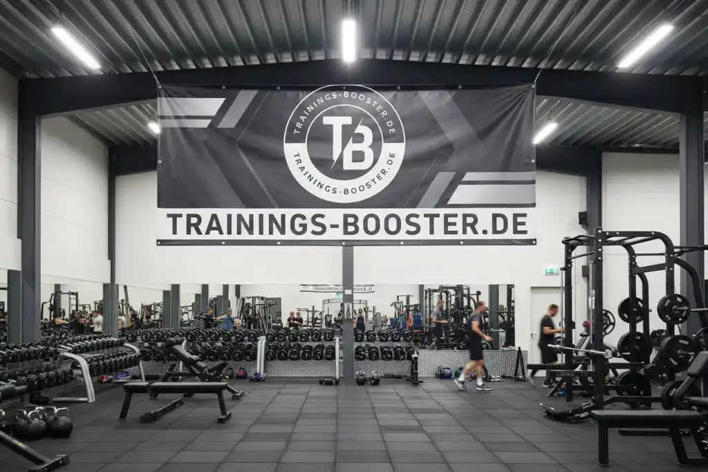 Modernes Fitnessstudio mit Hanteln und Trainingsgeräten unter einem Trainings-Booster.de Banner.