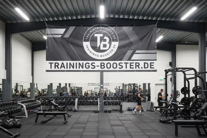 Modernes Fitnessstudio mit Hanteln und Trainingsgeräten unter einem Trainings-Booster.de Banner.
