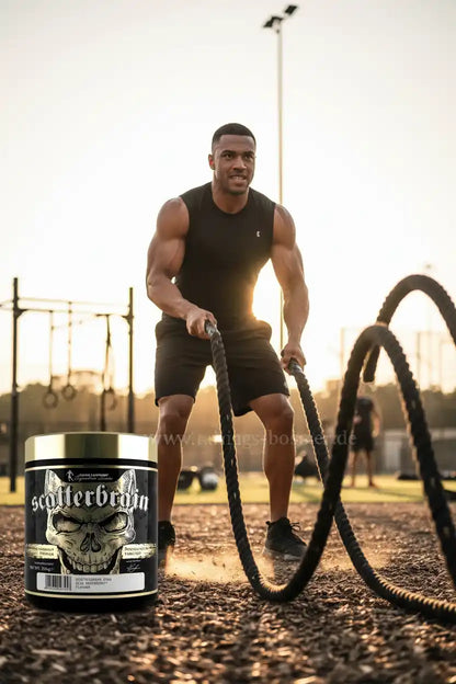 Muskulöser Mann mit Battle Ropes und Booster-Produkt im Fitnesspark