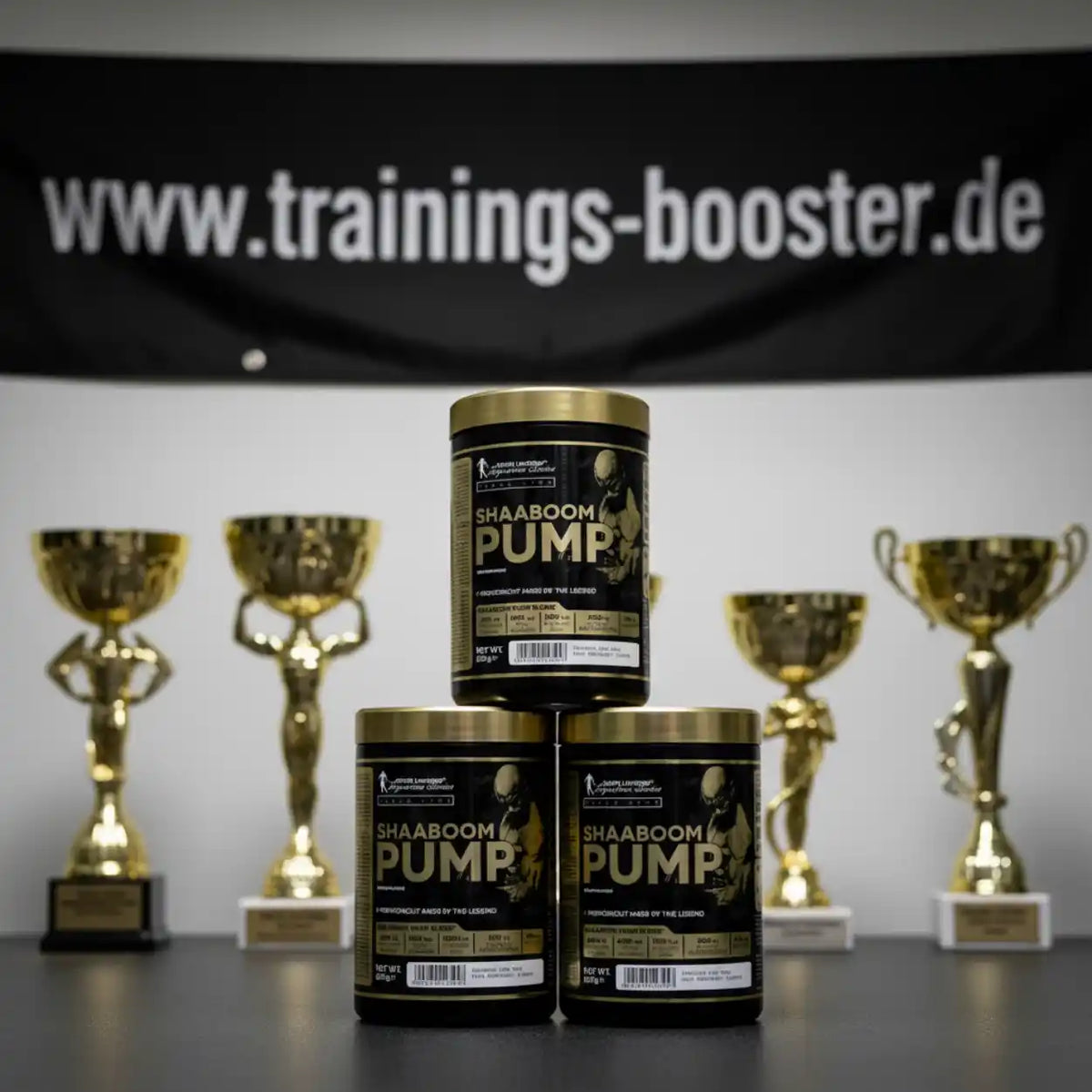 SHAABOOM PUMP Pre-Workout Booster mit goldenen Trophäen im Hintergrund – Sportnahrung für maximale Leistung